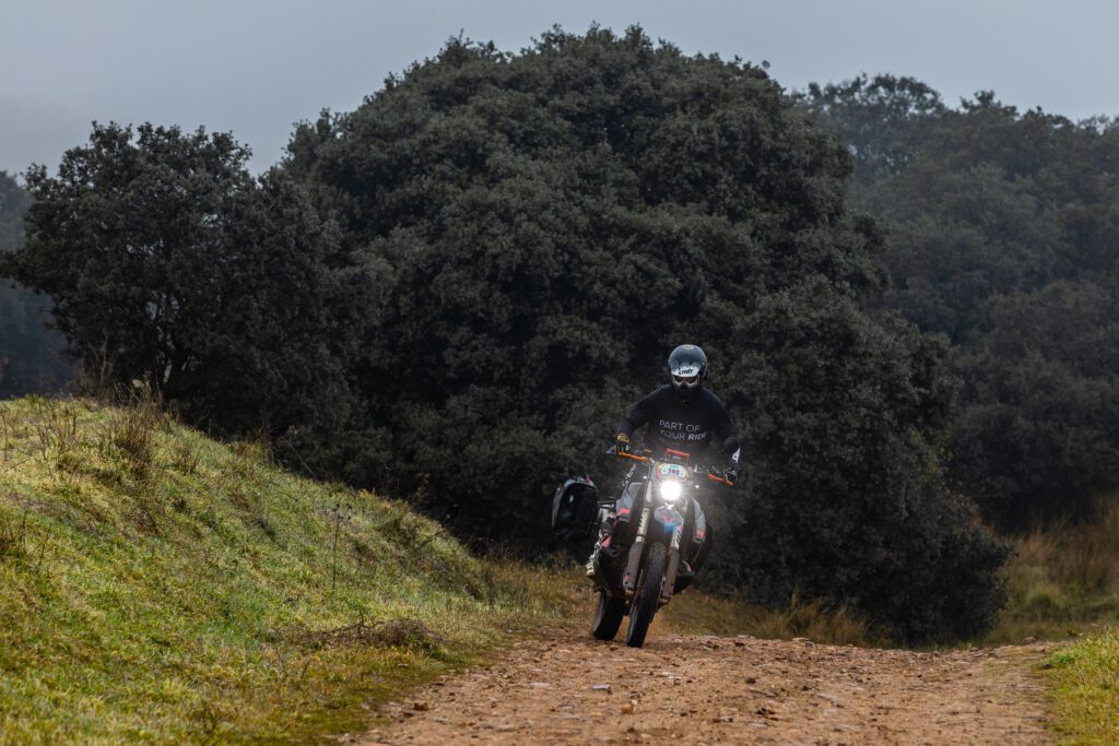 Moto KTM 890 Rally equipada con maletas Sysbag WP L de SW-Motech, avanzando por un camino rural rodeado de vegetación